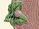 a pink plate with a green leaf on top of it