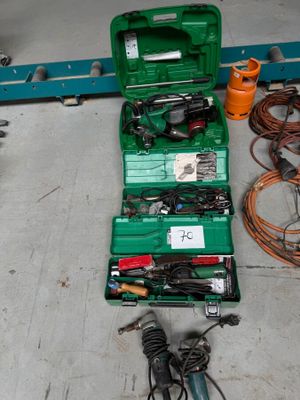 une mallette à outils verte posée par terre, contenant des outils