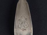 a silver spoon with a monogram on it on a black surface