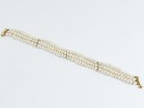 a close up of a white pearl bracelet on a white surface