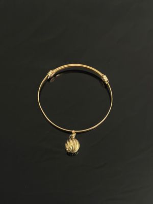 un bracelet rigide en or orné d'une boule en or sur fond noir