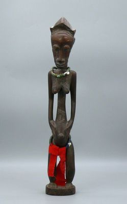 an image of a wooden statue of a woman with a red bag
