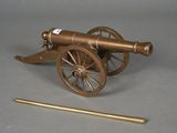 a small brass cannon with a wooden rod next to it