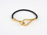 un bracelet en cuir noir avec un fermoir plaqué or sur fond blanc
