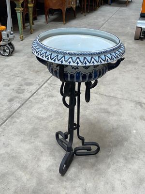 a blue and white bird bath on a black stand