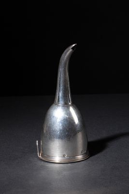a silver pitcher sitting on a table with a black background