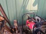 un homme debout à côté d'un tas de bois, avec un petit moteur