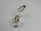 pair of gold wedding rings on clear acrylic stand