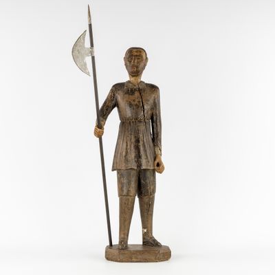 une statue en bois représentant un homme tenant une lance et un drapeau