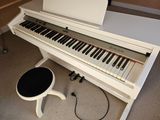 a white piano sitting on the floor next to a stool