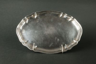 une assiette en argent posée sur une table noire, avec un fond noir