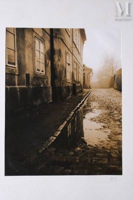 a black and white photo of a street with a puddle of water