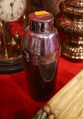 a silver cocktail shaker and a bunch of asparagus on a red table