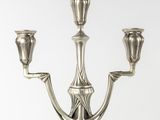 an antique silver candelier with three candles on a white background