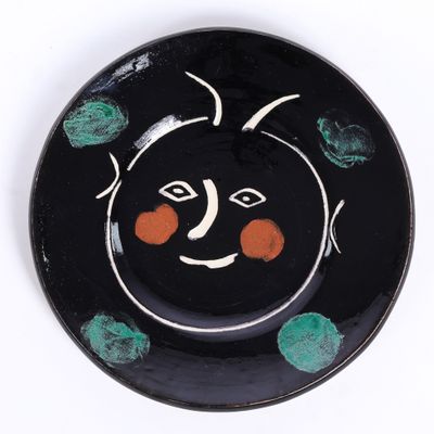 une assiette noire ornée d'un motif orange et vert