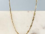 un collier à chaîne en or posé sur une surface en marbre