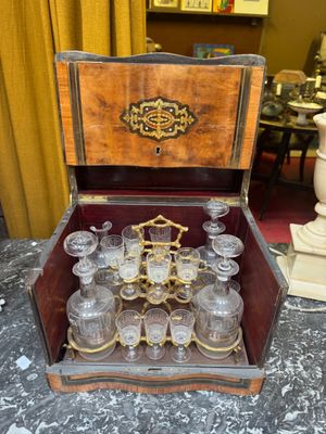 bottles and glasses in a wooden case sitting on a table