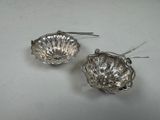 pair of silver shell shaped earrings on a white surface