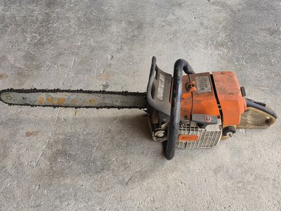 an orange chainsaw sitting on the ground in a concrete area