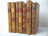several old books are lined up in a row on a white surface