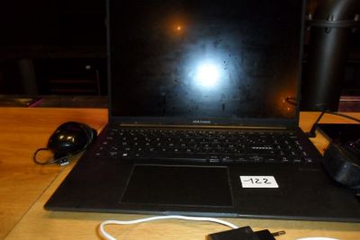 un ordinateur portable posé sur une table, avec un chargeur branché dessus