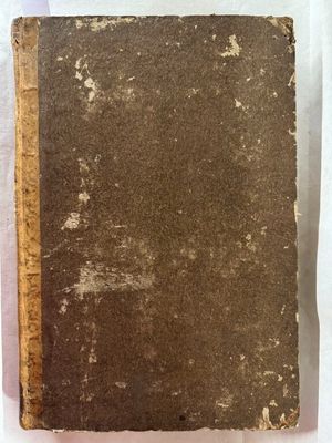 un vieux livre posé sur une table recouverte d'un tissu blanc