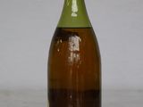 a bottle of wine sitting on a table with a white wall in the background