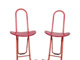 pair of red metal chairs against a white background