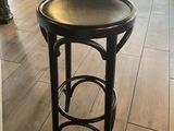 un tabouret noir posé sur le parquet d'un salon