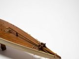 a small wooden surfboard on a stand on a white surface