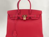 un sac à main en cuir rouge muni d'un cadenas sur la poignée