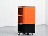 an orange and black cabinet on wheels in a white room