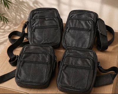 four black leather bags sitting on top of a wooden table