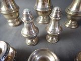 a lot of silver salt and pepper shakers on a table