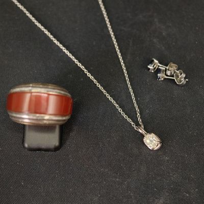un collier, une bague et une boucle d'oreille sur un fond noir
