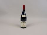 la bouteille de vin rouge est posée sur une surface blanche