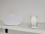 a white speaker sitting on a shelf next to a mouse