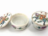 three porcelain bowls with lids are sitting on a white surface