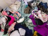 a pile of clothes that is sitting on a bed
