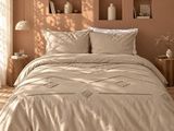 Le lit est fait avec une couette et des oreillers beiges.