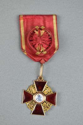une image représentant une médaille rouge et dorée ornée d'une croix