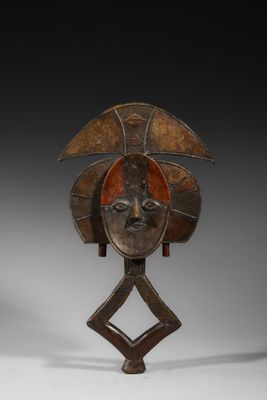 un masque en bois posé sur un socle et représentant un visage