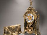une horloge en or posée à côté d'un sac à main sur une table