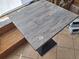 a wooden table with a metal base on a tiled floor