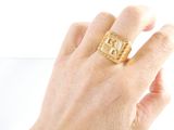 a person ' s hand holding a gold ring with a shell on it