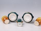 three small ceramic vases with lids and handles are sitting on a white surface