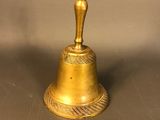 antique brass bell with a man on top of it sitting on a table