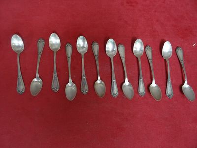 six cuillères en argent sont alignées sur une surface rouge