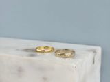 two gold rings sitting on top of a white marble block