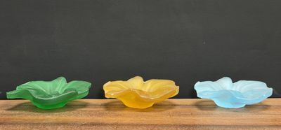 three different colored plastic flowers sitting on top of a wooden table